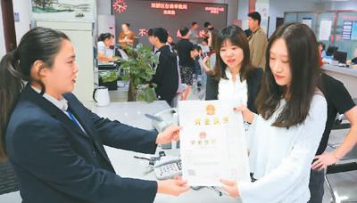 河北省承德市網(wǎng)絡(luò)代購(gòu)經(jīng)營(yíng)者陳晨(右)從工作人員手中接過(guò)帶有統(tǒng)一社會(huì)信用代碼的營(yíng)業(yè)執(zhí)照。 劉環(huán)宇攝(人民圖片)