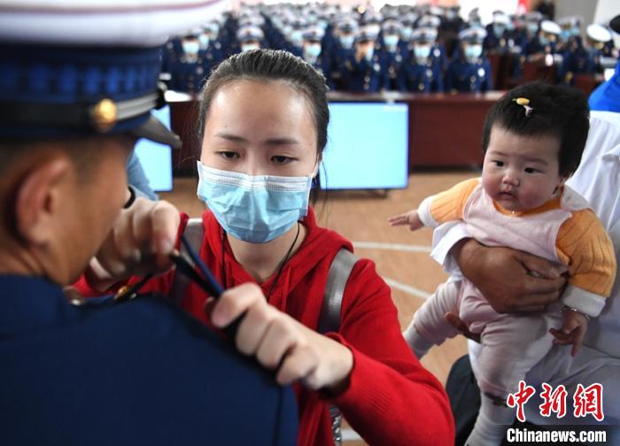 新消防員楊振的妻子彭莉與女兒現(xiàn)場見證丈夫加入“火焰藍(lán)”的神圣時(shí)刻。　劉忠俊 攝