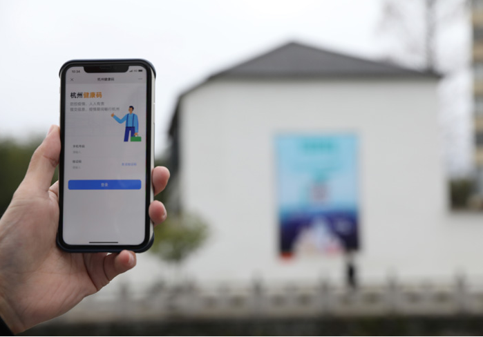 在浙江省杭州市臨安區(qū)天目山鎮(zhèn)，一名居民在“杭州健康碼”海報上掃碼申領(lǐng)個人二維碼。新華社發(fā)